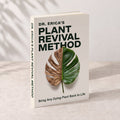 The book Dr. Erica’s Plant Revival Method. Its cover shows a monstera leaf that is dry on one half and green on the other